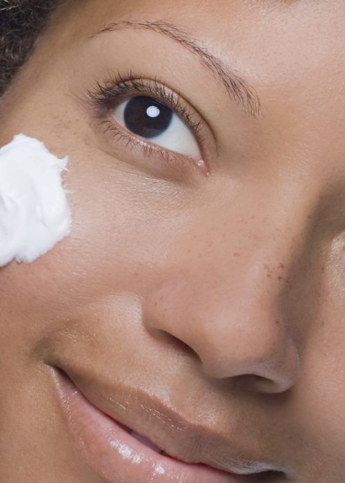 Attractive woman applying moisturizer